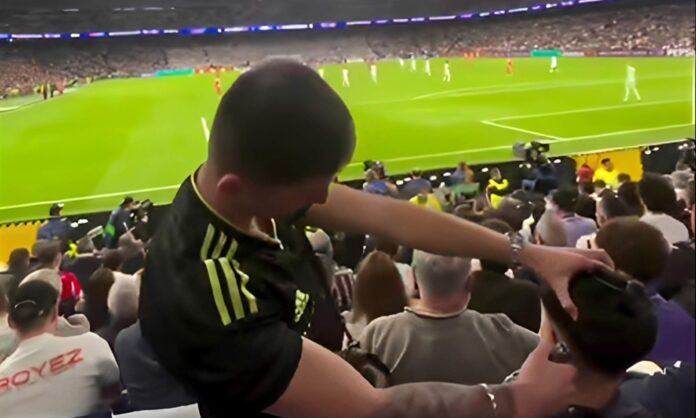 Un peluquero cortando el pelo a otro aficionado en el Santiago Bernabéu. 