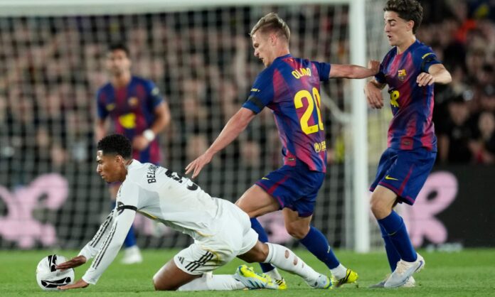 Dani Olmo empuja a Jude Bellingham para intentar adueñarse del balón, durante el partido de esta noche entre Barcelona y Real Madrid en el Camp Nou.